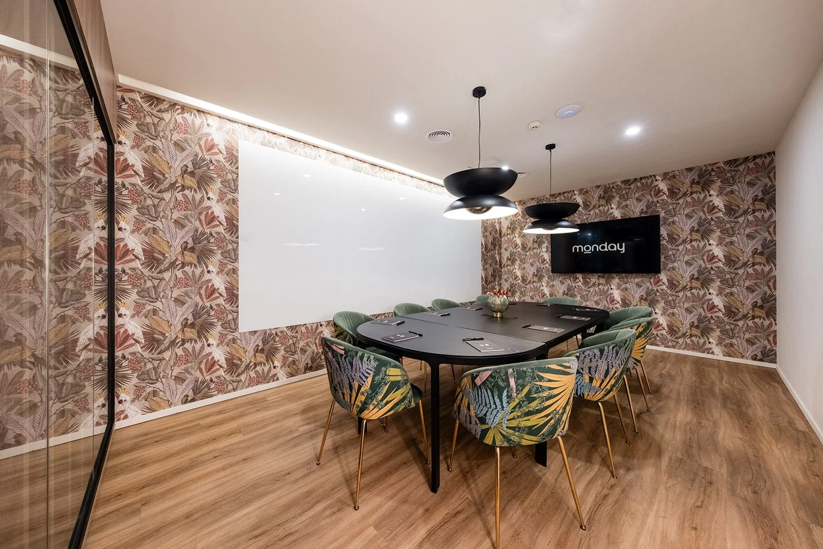 Sala de reuniones con mesa ovalada, sillas verdes y pantalla en Madrid