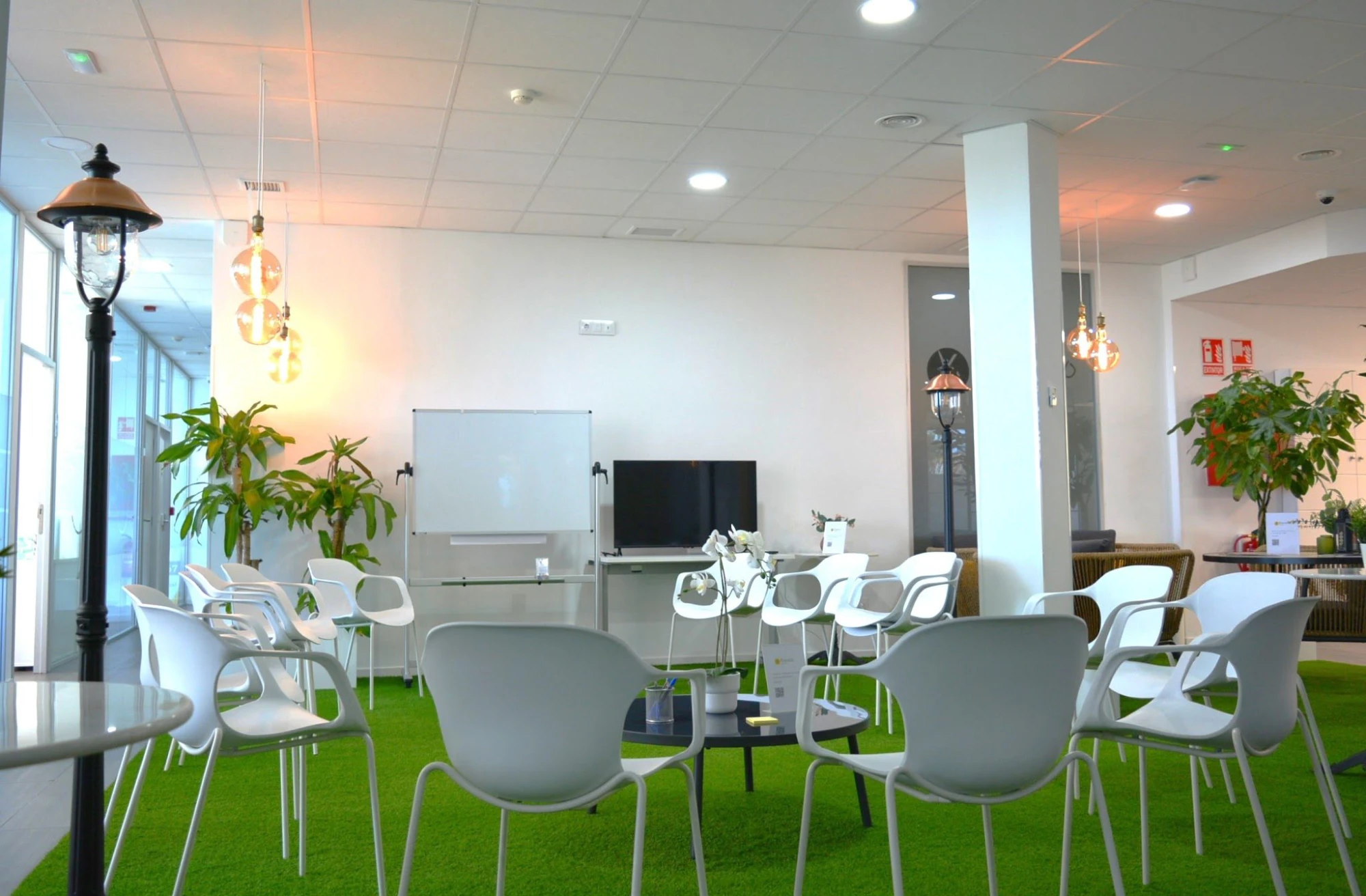 Sala con sillas en círculo, pizarra y suelo de césped artificial en Madrid
