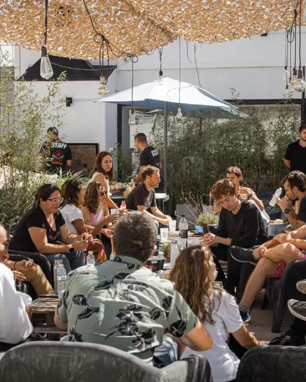 Terraza al aire libre con sombrillas y plantas, y un grupo de personas sentadas conversando, en Palermo, Buenos Aires