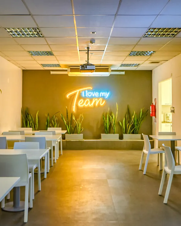 Auditorio con mesas, sillas, proyector y un cartel de neón que dice «I love my Team», en Retiro, Buenos Aires