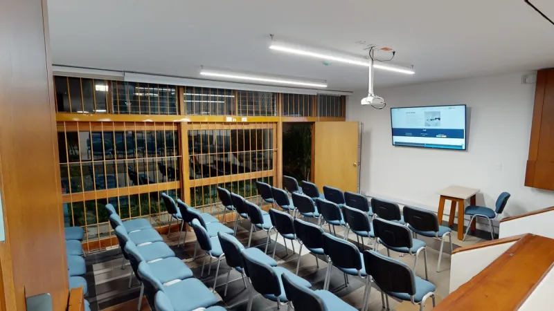 Auditorio con sillas azules en filas y pantalla en ArtWork Coworking, Bogotá