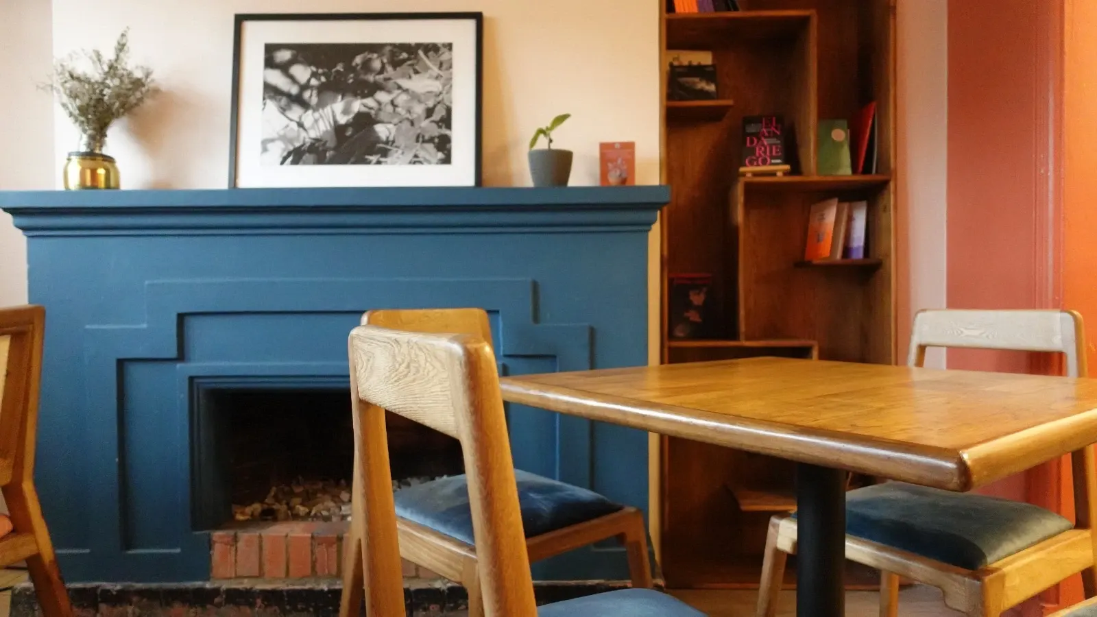 Café de trabajo en Bogotá con mesa y sillas de madera y una chimenea azul