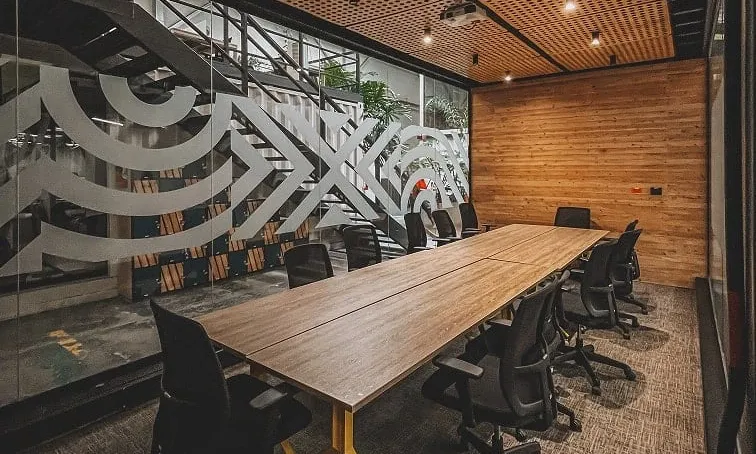 Sala de capacitación con mesa larga de madera y techo acústico en Bogotá