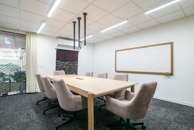 Sala de juntas con mesa de madera y sillas rosadas en Spaces Nogal, Bogotá