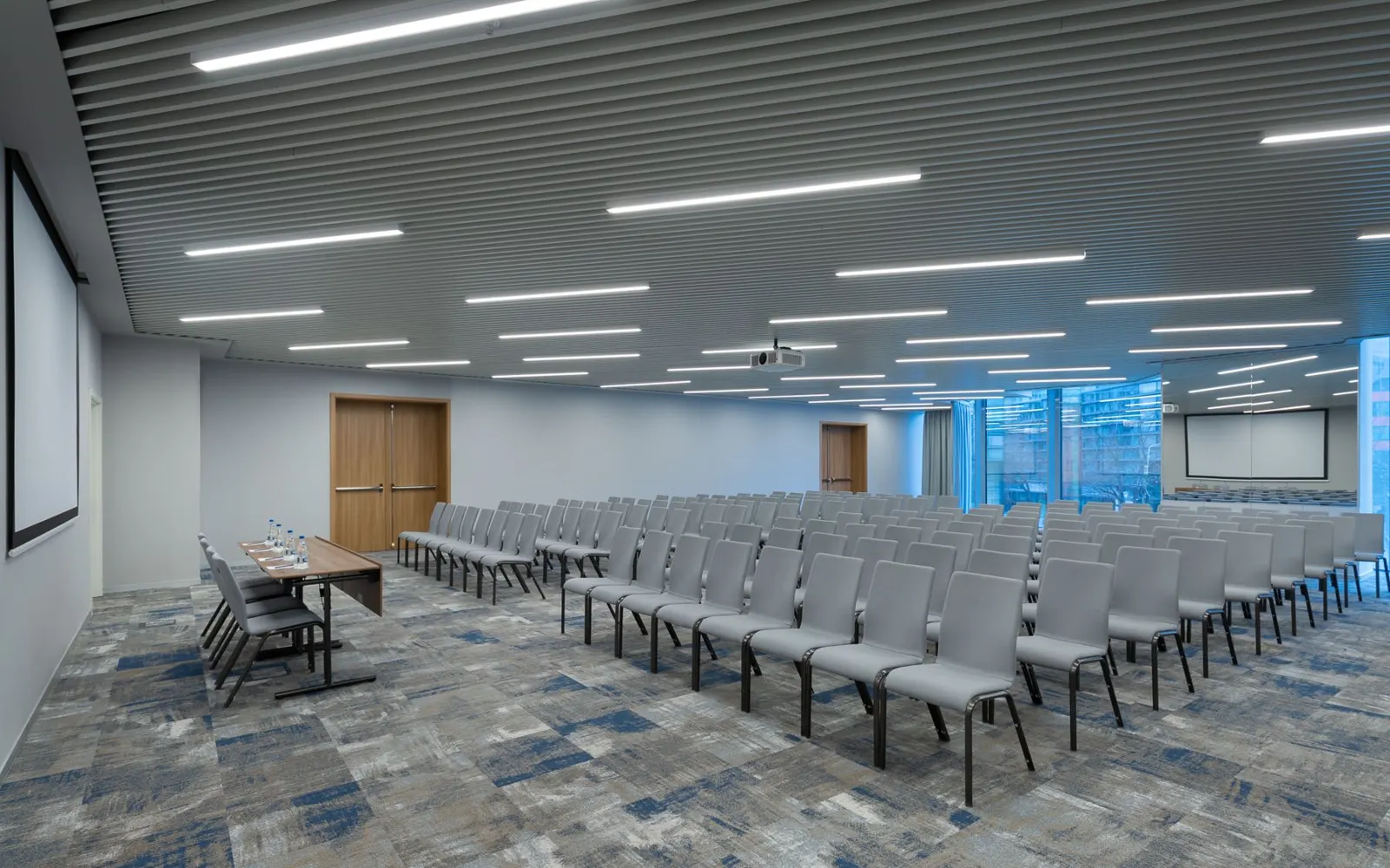 Sala de conferencias con sillas en filas, pantalla y proyector